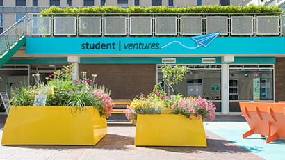 Exterior of the Student Ventures space entrance with bright orange concrete planters in front.