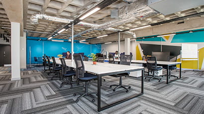 Innovation space with grey concrete ceiling and two large banks of tables.