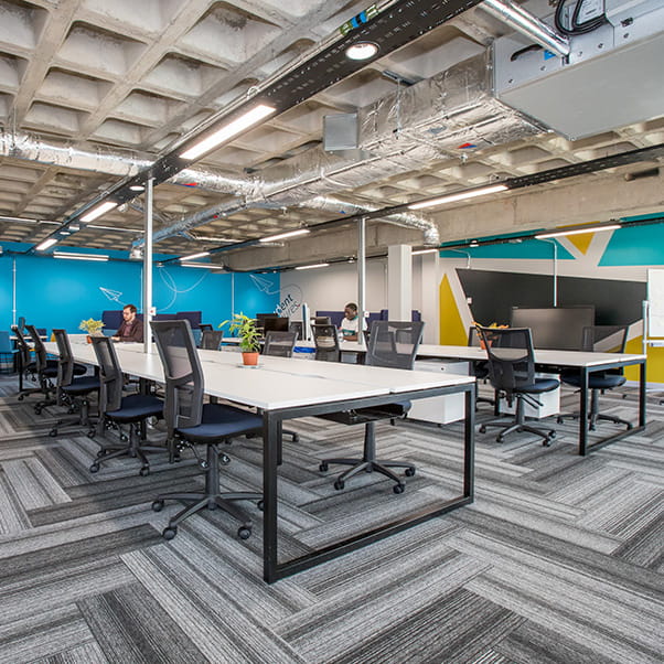 Innovation space with grey concrete ceiling and two large banks of tables.