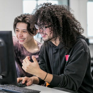 Two students using a computer in a study room.