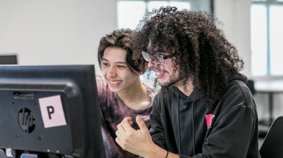 Two students using a computer in a study room.