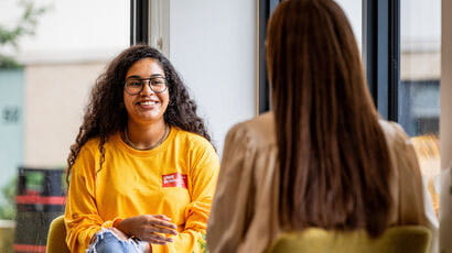 Smiling student talking to a member of staff.