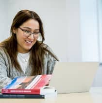 A student sits at a table working on a laptop.