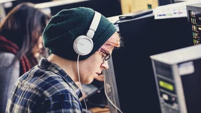 A student wearing headphones using a computer on campus.