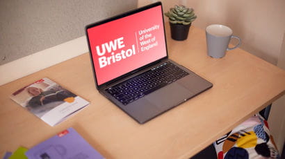 A student laptop with UWE Bristol logo on the screen, in student accommodation