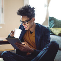 A man using a tablet while drinking out of a mug