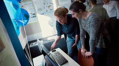 Two people pointing at a computer screen.
