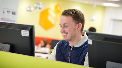 Male student on a computer in a computer cluster on campus