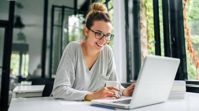 A student smiling whilst using a laptop.