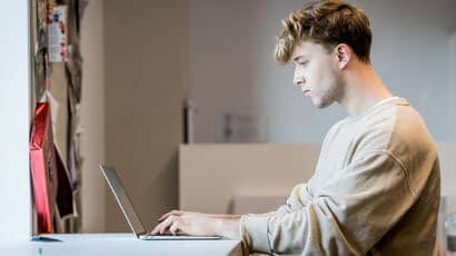 Students sat in his room at a desk working on his laptop.