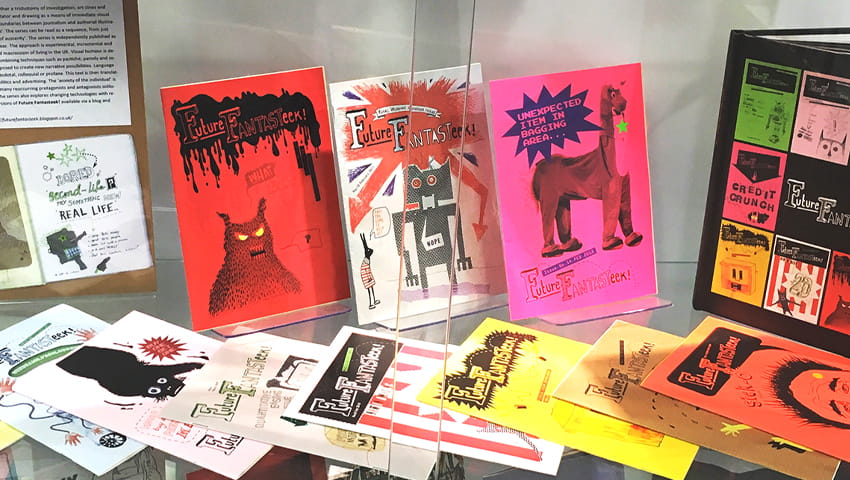 A collection of zines displayed in a glass cabinet.