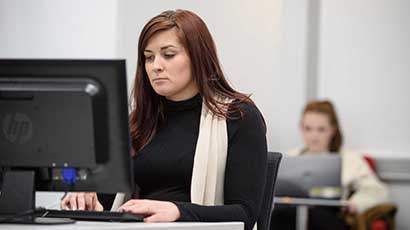 A student using a computer to browse library databases by subject.