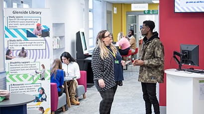 Staff and student talking in Glenside Library next to a Glenside library banner