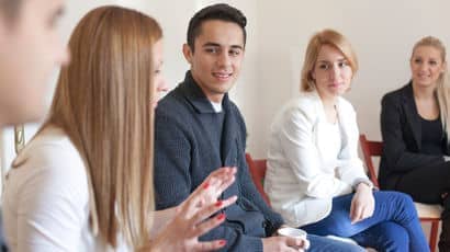 Group discussion between five students sitting on chairs in circle