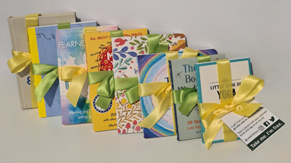 A set of 8 wellbeing and mindfulness books lined up with ribbon wrapped around them
