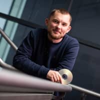 Portrait photograph of Kieran Devlin holding a CD.