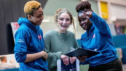 Two students helping a third with directions.