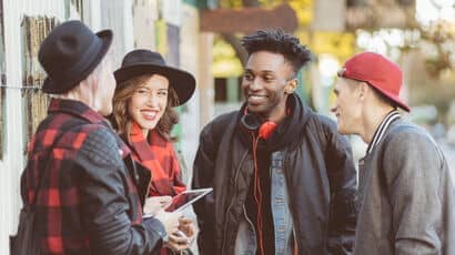 Four students smiling together on campus.