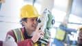 A student in protective gear surveying construction site alongside other students