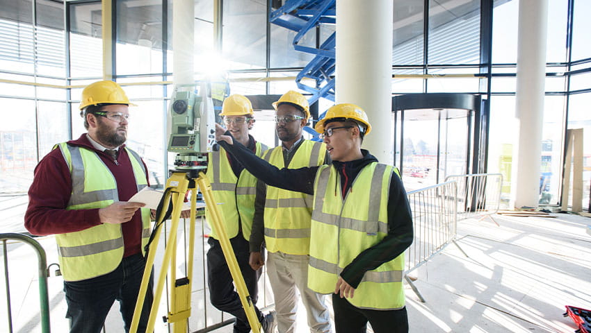 Four students in protective gear surveying inside a building that is under construction