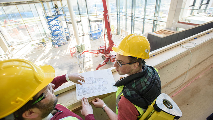 A student and an instructor surveying inside a building, they all wear protective gear