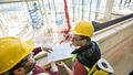 A student and an instructor surveying inside a building, they all wear protective gear