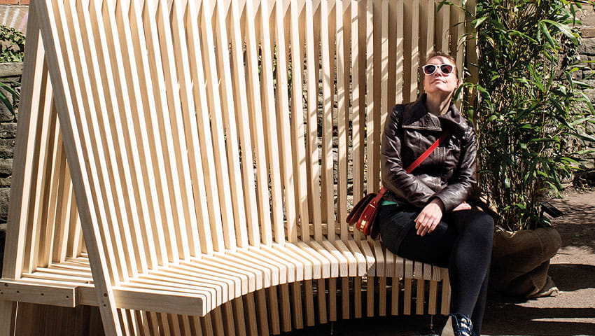 A person sitting on the edge of a wooden chair with creative and modern design