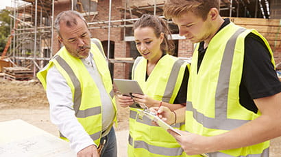 Students wearing high-vis vests on a building site.