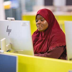 International student looking at a pc in the library.