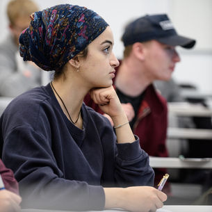 Student holding a pen while sitting at a desk.