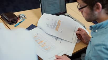 Student reading through a report with highlighted passages.