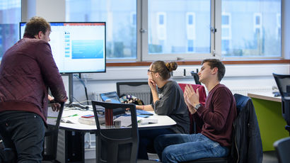 Students having a conversation with a member of staff in the library.