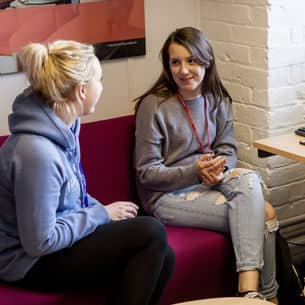 Two students talking in a common room.