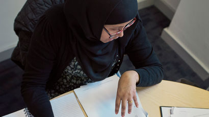 Student sat in a study space writing in a notepad.