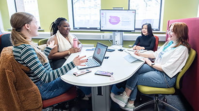 Group of students working around a TEAL desk on a presentation