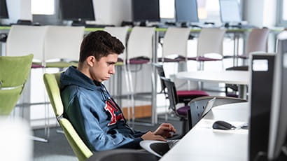 Student working on a laptop in a study lounge