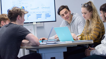 A group of students working on laptops in a study room.