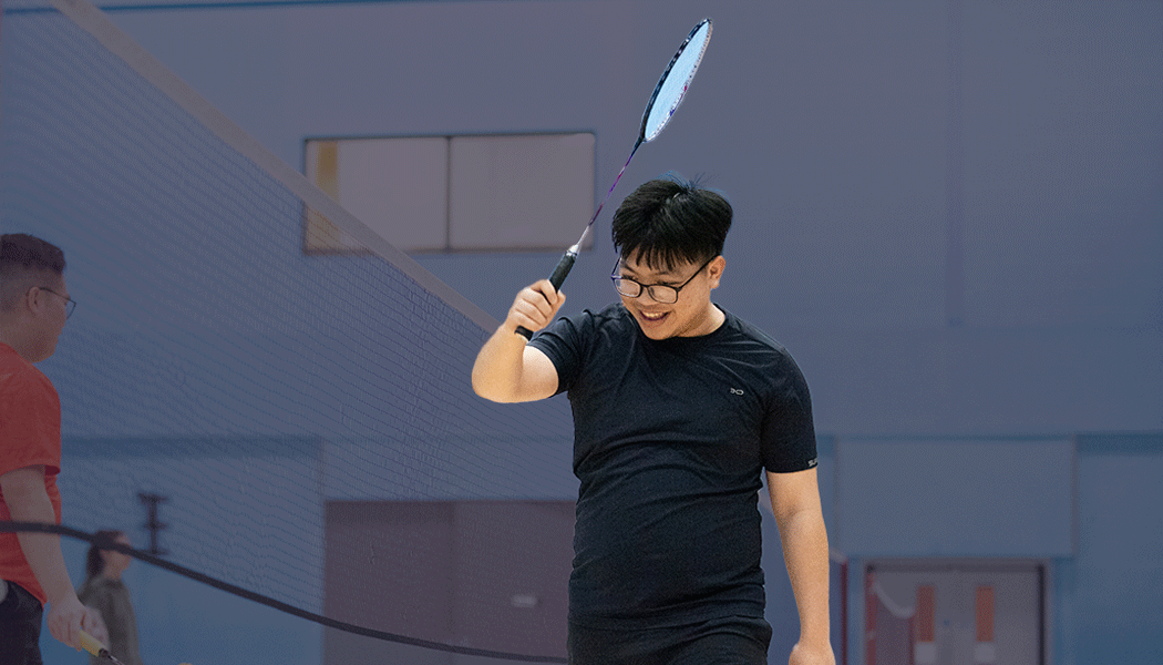 Man holding his badminton racket high as he celebrates a point.