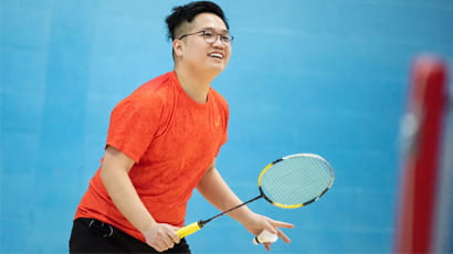 Male student prepares to serve during a badminton match.