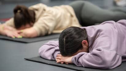 Two students lying face down on the floor in a studio