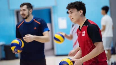 Two UWE Bristol Sport students playing volleyball on an indoor court.