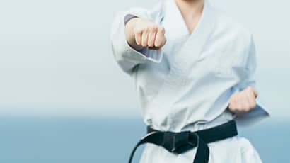 Photo of female in karate uniform punching towards the camera.