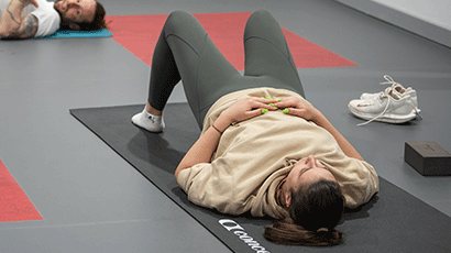 A relaxed student lying on a yoga mat in a yoga studio.