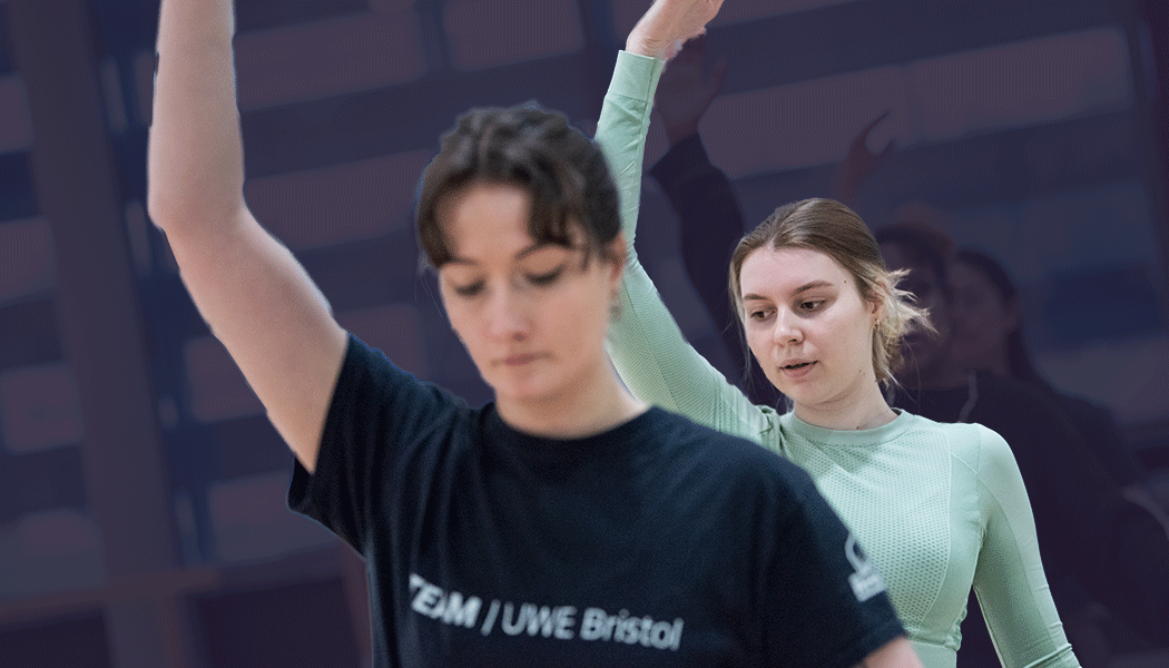 People in an exercise studio holding arms overhead in a pose.