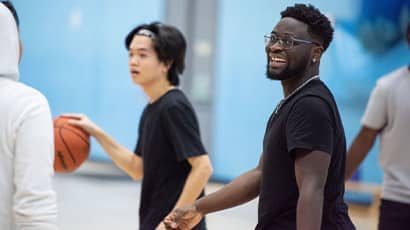 A group of young men playing basketball together in a sports hall.