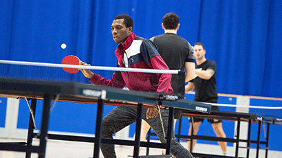 A man holding his table tennis bat ready to hit a forehand across the table.