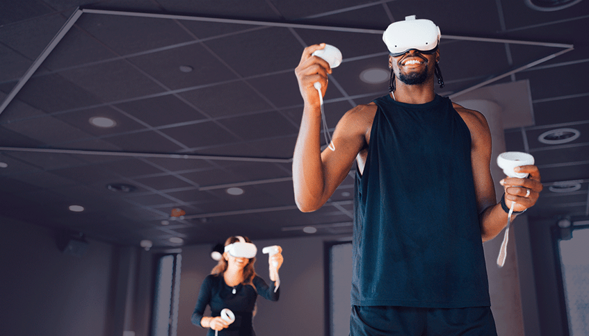 Two people in an exercise studio holding controllers and wearing VR headsets.