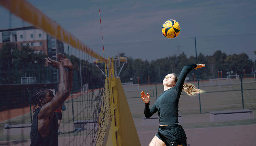 A woman leaping in front of an outdoor volleyball net, raising her arm to the ball. 