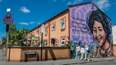 Students walking under graffiti depicting Carmen Beckford MBE in Bristol.