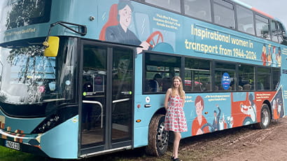 UWE Bristol illustration student stands in front of a double decker bus featuring her winning design 